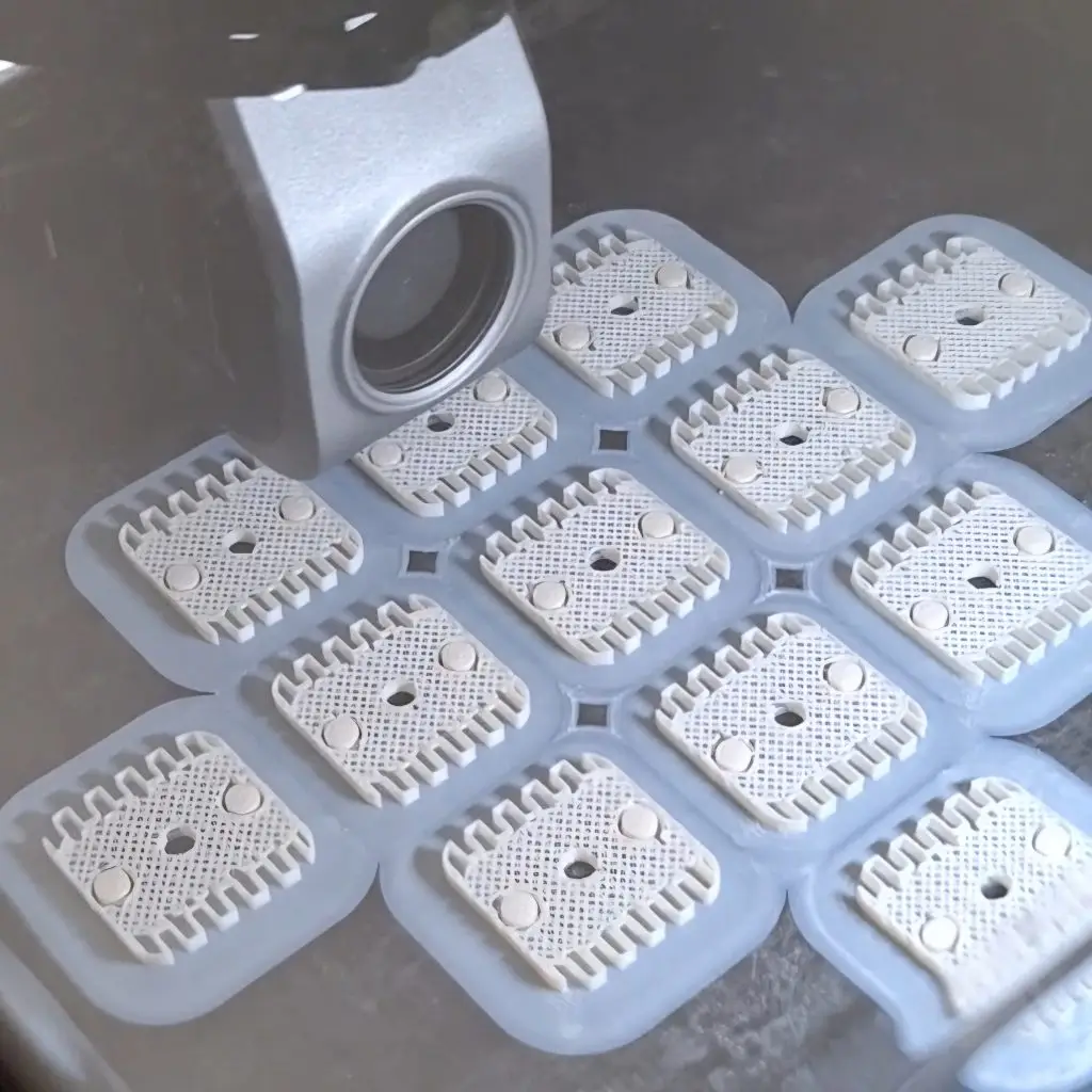 Imprimante FDM en cours d'impression d'une petite série de pièces techniques blanches